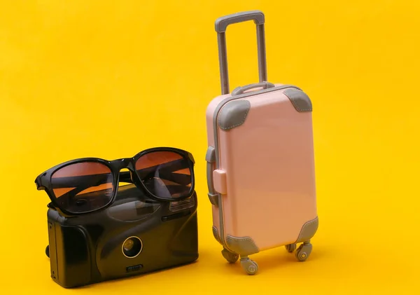 Travel Concept Mini Pink Plastic Travel Suitcase Camera Sunglasses Yellow — Stock Photo, Image