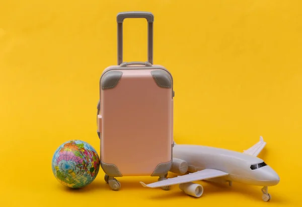 Vliegreis Concept Mini Roze Plastic Reiskoffer Vliegtuig Wereldbol Gele Achtergrond — Stockfoto