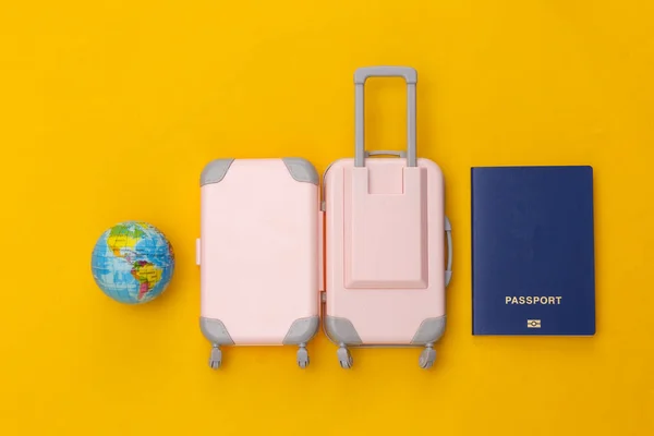 Een Lekke Band Mini Plastic Reiskoffer Wereldbol Paspoort Gele Achtergrond — Stockfoto