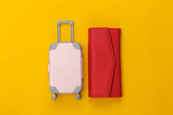 旅行平铺 迷你塑料旅行箱 红色皮夹黄色背景 简约的风格顶部视图 — 图库照片