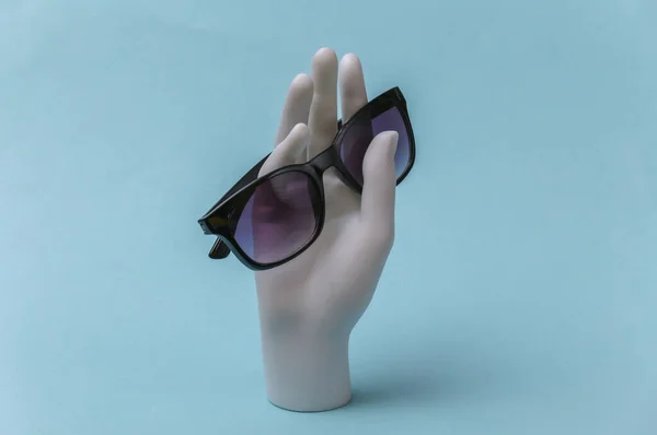 Weiße Schaufensterpuppe Hand Hält Sonnenbrille Auf Blauem Hintergrund — Stockfoto