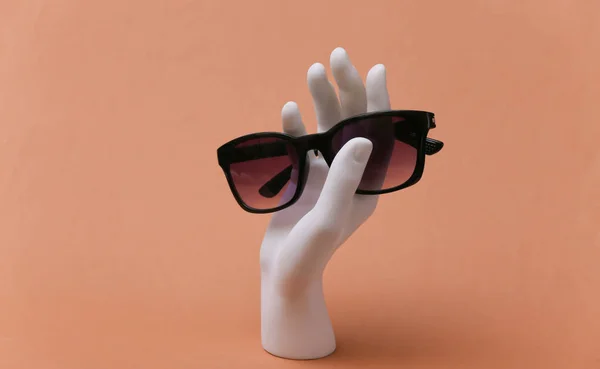 Biała Ręka Manekina Posiada Okulary Przeciwsłoneczne Brązowym Tle — Zdjęcie stockowe