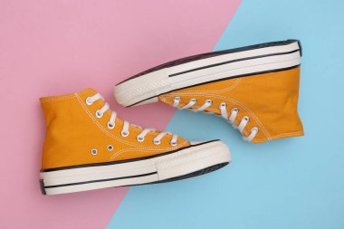 Pembe mavi arka planda Retro Yellow yüksek topuklu ayakkabılar (Gumshoes). Üst Manzara. Minimalizm