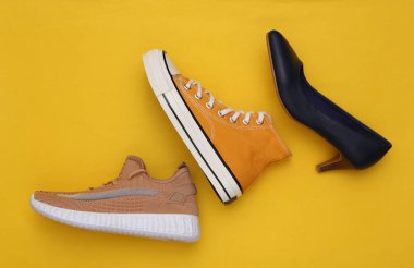 Sarı arka planda farklı kadın ayakkabıları. Üst görünüm