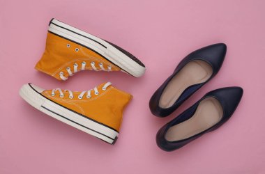Pembe arka planda topuklu ayakkabı ve spor ayakkabılar. Kadın ayakkabıları. Üst görünüm