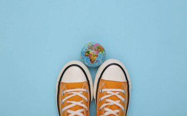 Mavi arka planda küresi olan Retro ayakkabılar (Gumshoes). Seyahat konsepti. Üst görünüm