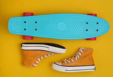 Sarı arka planda kruvazör tahtası ve ayakkabı. Gençlik konsepti. Üst görünüm