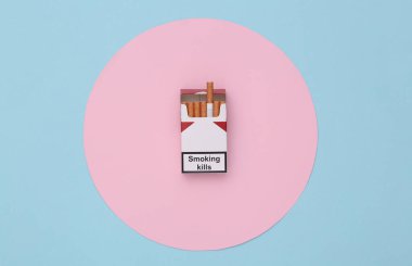 Mavi arka planda pembe daireli bir paket sigara. Sigara öldürür. Üst görünüm