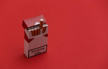 Kırmızı arka planda bir paket sigara. Sigara öldürür..