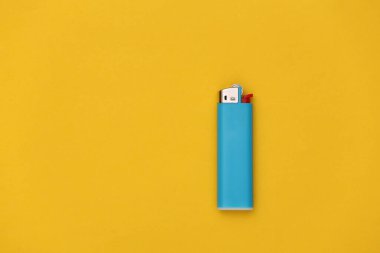 Sarı arka planda plastik gaz çakmağı. Üst Manzara. Minimalizm