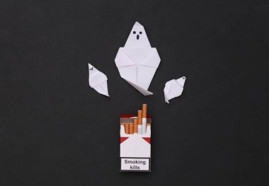 Sigara öldürür. Siyah arka planda bir paket sigara ve hayalet.