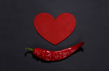 Siyah arka planda kırmızı biber ve kalp. Aşk konsepti. Üst görünüm
