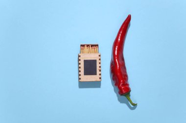 Baharatlı kırmızı biber ve mavi arka planda kibrit.