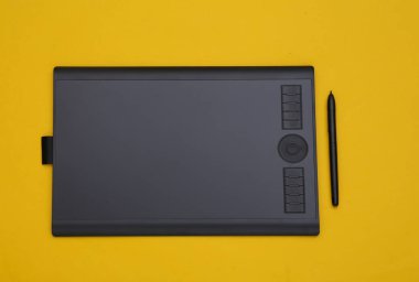 Sarı zemin üzerinde kalem olan grafiksel tablet. Üst görünüm