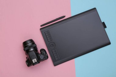 Pembe mavi zemin üzerinde kalem ve kamera olan grafiksel tablet. Üst görünüm