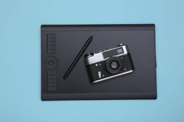 Mavi zemin üzerinde kalem ve kamera olan grafiksel tablet. Üst görünüm