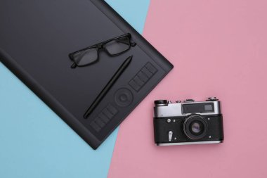 Pembe mavi zemin üzerinde kalem ve kamera olan grafiksel tablet. Üst görünüm