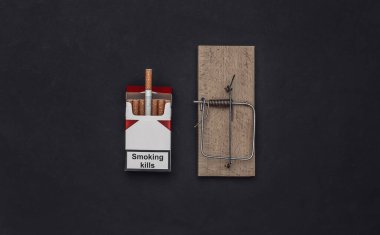 Sigara bağımlılığı. Fare kapanı ve siyah arka planda bir paket sigara.