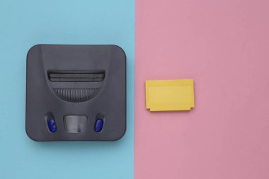 Retro video oyun konsolu, mavi pembe arka planda kartuşlar. Üst görünüm