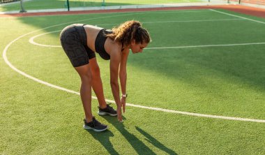 Açık hava eğitimi. Çekici seksi fitness modeli antrenmandan önce kasları ısıtır ve gerer.