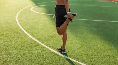 Açık hava eğitimi. Çekici kadın antrenmandan önce bacağını esnetir.