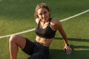 Çekici sporcu kadın sıkı çalışmadan sonra çimenlerde dinleniyor.