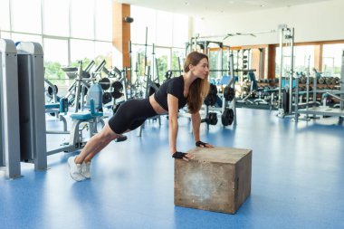 Modern jimnastik salonunda şınav çeken sıska bir kadın. Atletik kız egzersizi. Çapraz eğitim