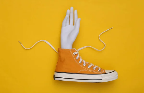 Concept Kunst Sneaker Met Mannequin Hand Gele Achtergrond — Stockfoto
