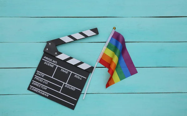Lgbt gökkuşağı bayrağı, mavi ahşap arka planda film alkış tahtası. Hoşgörü. Görüntü yönetmeni, film yapımcısı. Üst görünüm.
