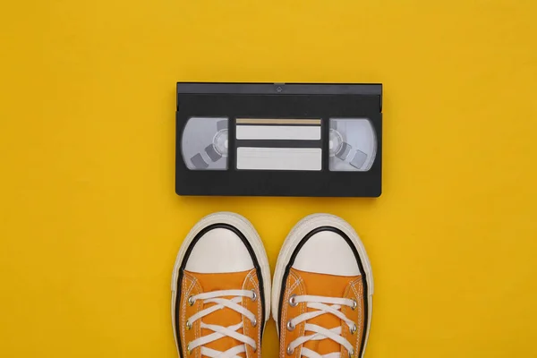 스니커즈 Gumshoes 노란색 배경에 비디오 카세트를 위에서 나막신 — 스톡 사진