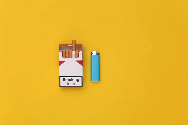 一包香烟和黄色背景的打火机 吸烟使人死亡 顶部视图 — 图库照片