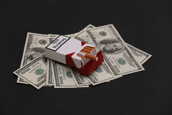 一包香烟 背景是黑色的100美元钞票 吸烟成本 — 图库照片