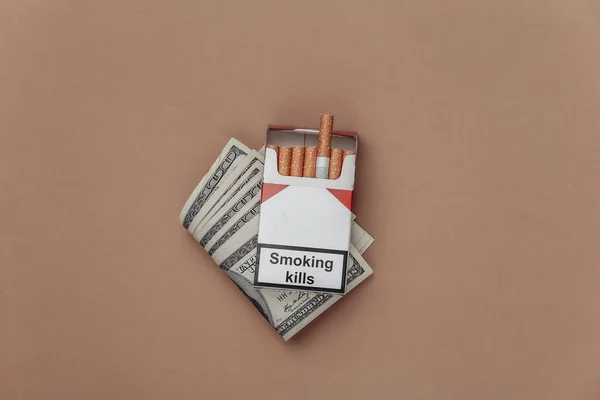 一包香烟 背景是褐色的一百元钞票 吸烟成本 — 图库照片