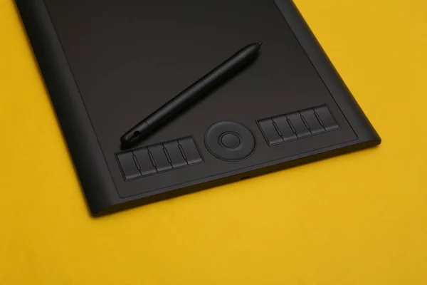 黄色の背景にペン付きのグラフィックタブレット — ストック写真