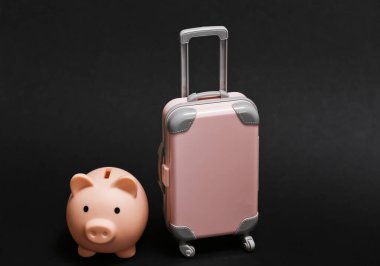 Seyahat ya da seyahat konsepti. Mini plastik seyahat valizi ve siyah arka planda kumbarası. Asgari biçim