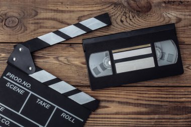 Tahta arka planda film alkışları ve video kaset. Sinema endüstrisi, eğlence. Üst görünüm