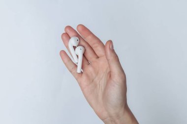 Beyaz arka planda kadın avucunda kablosuz kulaklıklar.