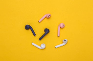 Different colors Wireless headphones on yellow background. Top view. Minimalism clipart