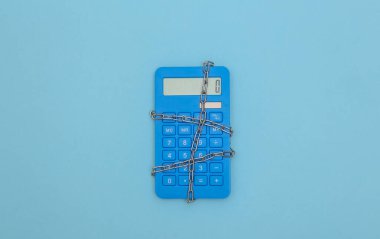 Sarı arka planda çelik zincire sarılı hesap makinesi. Üst görünüm