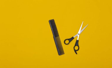 Sarı arka planda tarak ve makas. Berber aleti. Üst görünüm