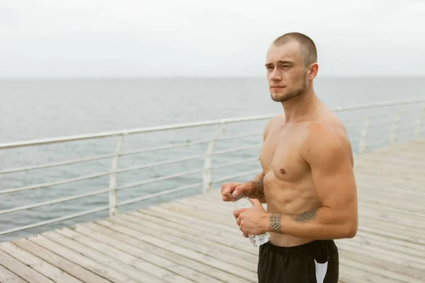 Muskulös Manlig Idrottsman Som Håller Flaska Vatten Stranden — Stockfoto