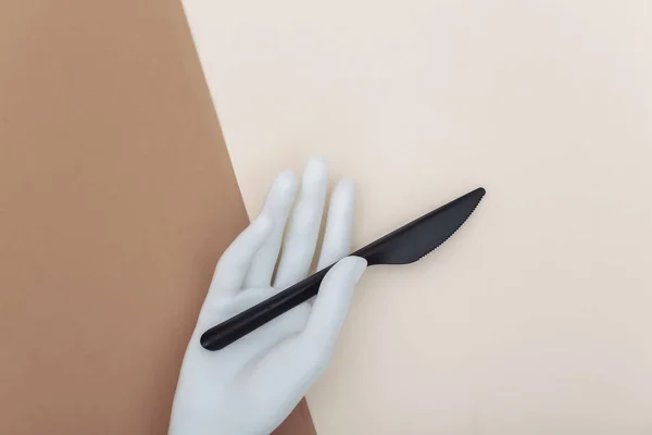 Weiße Schaufensterpuppe Hand Hält Ein Plastikmesser Auf Beige Braunem Hintergrund — Stockfoto