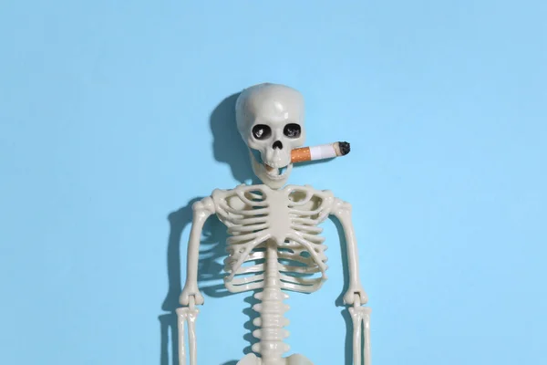 在明亮的蓝色背景下 嘴里衔着香烟的吸烟骷髅 吸烟使人死亡 — 图库照片