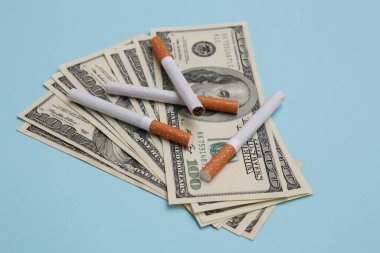 Mavi arka planda 100 dolarlık sigaralar.