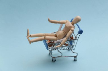 Sigaralı mini market arabası ve mavi arka planda tahta kukla.