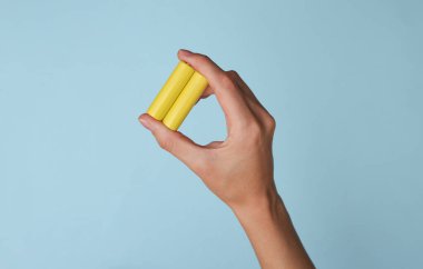 Mavi arka planda bir batarya tipi el ele tutuşur.