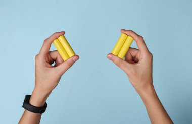 Eller mavi arka planda a tipi pil tutuyor.