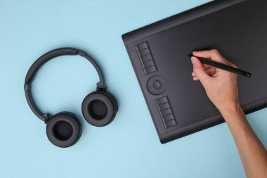 Kadın grafik tasarımcısı ya da rötuş uzmanı mavi arka planda grafik tabletle çalışıyor. Üst görünüm