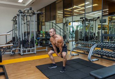 Egzersiz odaklı, kaslı, modern spor salonunda kettlebell salıncakları yapan adam. Vücut geliştirme kuvveti eğitimi