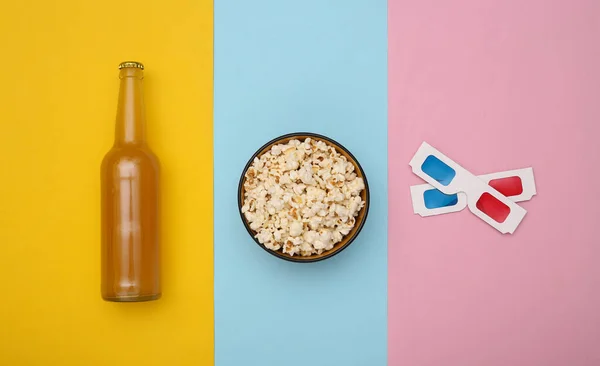 Movie time. Beer bottle and Bowl with popcorn, 3d glasses on colored background. Top view